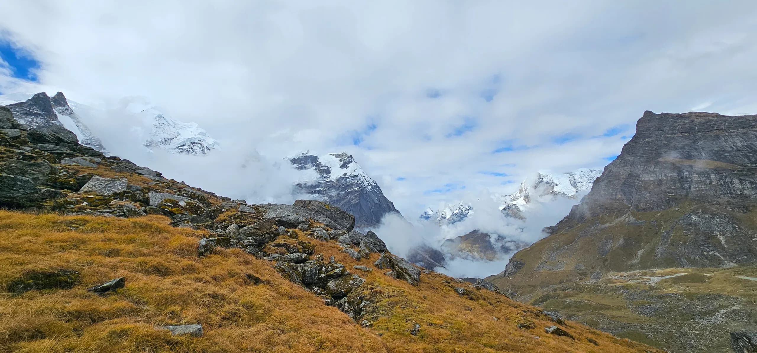 Golden alpine slopes above Khare with the snow-covered Mera massif behind clouds